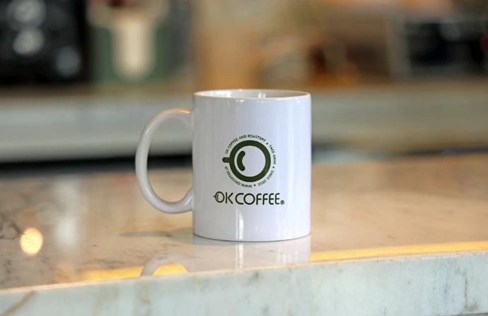 A white mug with "ok coffee" logo on counter